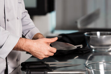 Chef man hands with knife. Closeup hands of male professional in uniform.