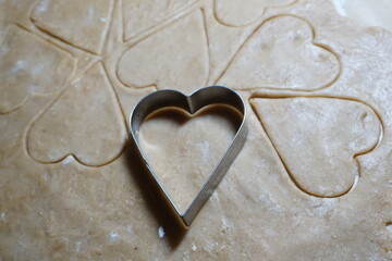 Heart shaped cookie cutters cutting out holiday cookies.