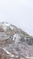 Fototapeta na wymiar Vertical crop Provo Canyon mountain with steep rugged slopes dusted with snow in winter