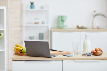 Image of kitchen table with fruits and laptop computer on it in domestic kitchen