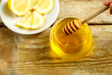 Spoon for honey with drops of honey in a female hand.