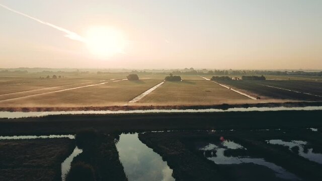 Aerial shot of the rural dutch countryside with fog at sunrise, Netherlands. Water and dikes with birds. High quality FullHD footage