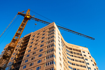Fototapeta premium Crane build high-rise skyscraper apartment against blue sky