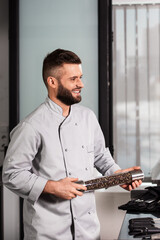 Chef man with pepperbox at kitchen. Smiley professional with pepperbox.