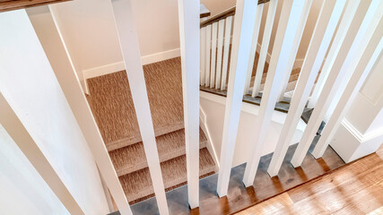Fototapeta na wymiar Panorama crop White wooden baluster and brown handrail of U shaped staircase inside a home