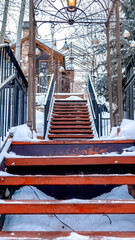 Vertical frame Close up of stairway on snow covered slope with buildings and trees background
