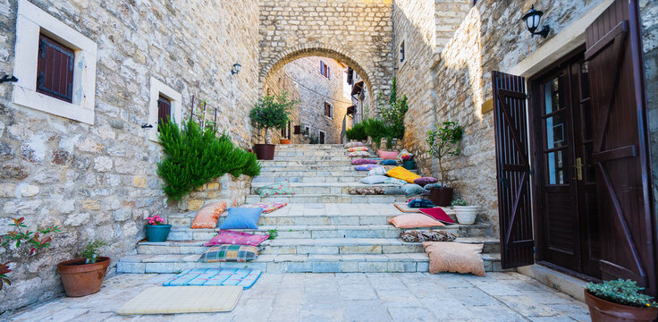 Stairs with pillows and stone arch in Ulcinj Old Town, Montenegro. Banner and panoramic edition. Selective focus.