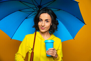 Enjoying myself. Half-length photo of beautiful girl dressed in a yellow hoodie under an umbrella,...