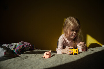 Portrait of a playing girl at home in the sun on a yellow wall