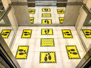 Yellow caution signs on elevator floor to keep social distancing between passenger during Covid-19 pandemic outbreak 