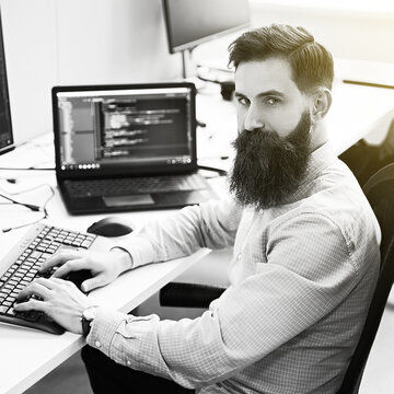 Serious computer programmer developer working in IT office, sitting at desk and coding, working on a project in software development company or startup. Black and white,