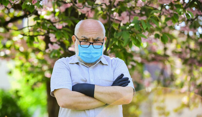 Pandemic concept. Older people at highest risk from covid-19. Limit risk infection spreading. Senior man wearing face mask and gloves outdoors. Infection is in air. Protect and from virus infection
