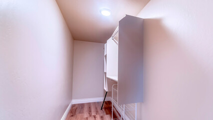 Panorama Walk in closet with metal rod and shelves on the wall mounted white cabinet