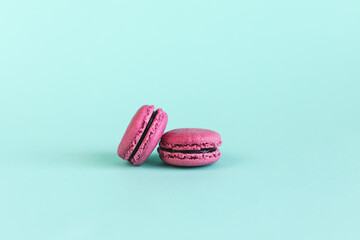 Tasty pink french pink macaroons on a turquoise background.