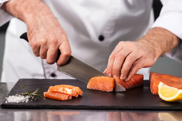 Chef male cutting fish fillet. Closeup chef hands slicing salmon.