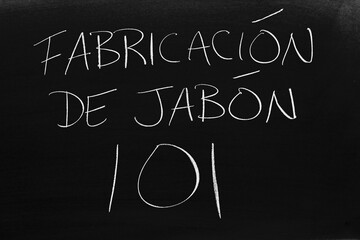 The words Fabricación De Jabón 101 on a blackboard in chalk.  Translation: Soap Making 101