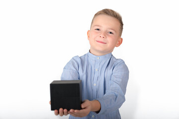 Smiling caucasian blond boy in blue shirt holds black box.the box is in front.Isolate white background.Close up.
