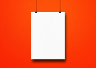 White poster hanging on a red wall with clips