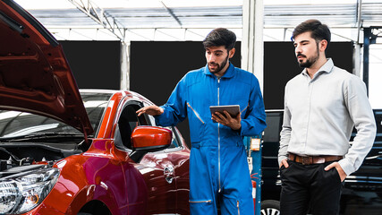 Mechanic man shows report on a digital tablet to the Middle East client at garage, A man mechanic and client discussing repairs done to his vehicle. Changing automobile business.