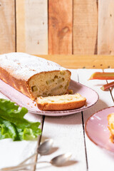 geschnittener, frischer Kuchen mit Rhabarber, Puderzucker und Eierlikör auf einem Tisch aus Holz in der Küche am Nachmittag