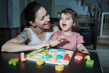 A mother teaching her daughter the letters of the alphabet