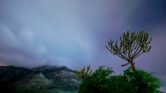 Night time lapse of clouds rolling over mountains