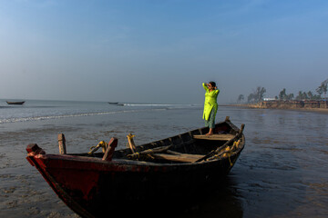 An woman standing on a boat on a sea beach
