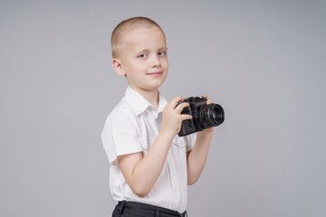 Child boy with retro compact camera, isolated on gray background.