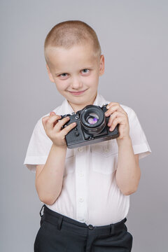 Child boy with retro compact camera, isolated on gray background.