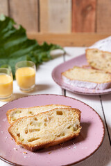 geschnittener, frischer Kuchen mit Rhabarber, Puderzucker und Eierlikör auf einem Tisch aus Holz in der Küche am Nachmittag