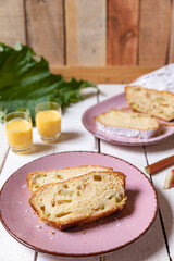 geschnittener, frischer Kuchen mit Rhabarber, Puderzucker und Eierlikör auf einem Tisch aus Holz in der Küche am Nachmittag