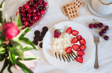 Sweet ripe strawberries and fresh cottage cheese on a white plate. A full bowl of cherries and shortbread cookies.