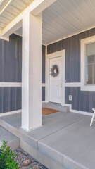 Vertical frame White porch chairs against window and front door of home with gray exterior wall