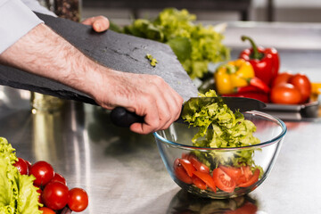 Chef hands cook food at kitchen restaurant. Closeup male hands mix vegetables.