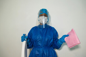 Woman in blue protective suit, medium mask, rubber gloves and goggles. Liquid spray on the hands. The concept of disinfection, the fight against the virus COVID-19.