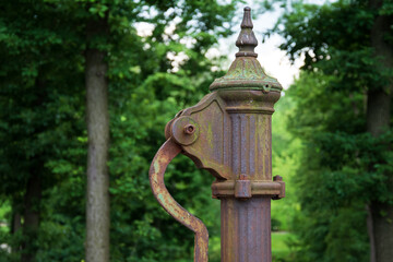 Fototapeta premium hand water pump. Old Manual pump well in park. Photo of old style well object. Old Antique metal mechanism.