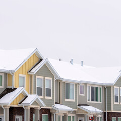 Square frame Facade of townhomes with snow covered pitched and valley roof against cloudy sky