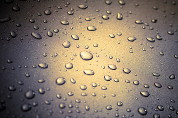 Large drops of dew on a Golden leaf. Raindrops on tinted glass, close-up. Abstract background, large water drops, selective focus.