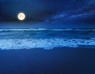 beach and sea on a cloudy night. beautiful view of waves rolling the coast beneath a glowing sky in full moon light