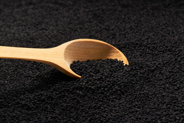 wooden spoon filled with black caraway seeds. food background.