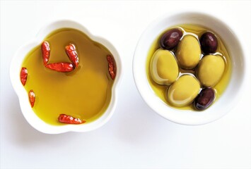 Red chili pepper and green and black olives on olive oil bowls. photo isolate on white top view copy space  