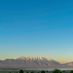 Naklejka premium Square Vibrant blue sky over snow capped mountain and lake on a scenic nature landscape