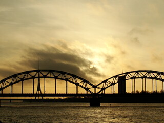 Railway bridge through Daugava in Riga, Latvia. Beautiful view of the big river and sunset though the clouds.