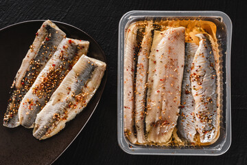 Marinated fillet mackerel or fillet herring fish with spices packed in box on plate over slate...