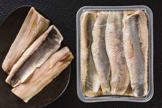 Marinated fillet mackerel or fillet herring fish with oil packed in box on plate over slate stone background. Mediterranean food, appetizer, seafood, top view