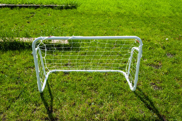 Mini football goal on the green grass on a plot near the house. Family play