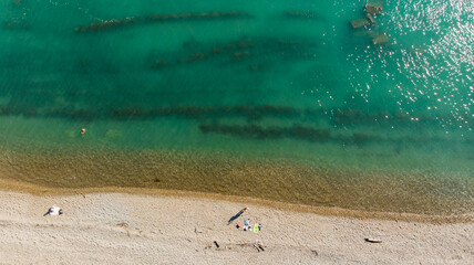 The expanse of the sea meets the sandy beach. Soft sea waves of blue transparent water on the beach. A soft wave of blue tropical beach serenity, a natural backdrop for summer holidays. Aerial view fr