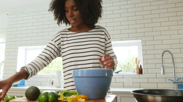 Beautiful young woman cracking eggs, mixing and baking in the kitchen at home