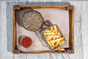 Tasty hamburger with french fries and sauce on a wooden tray