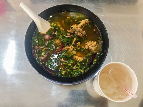Hot and spicy soup with pork ribs, or Tom Saeb Kraduk Moo, Thai style food. Tom yum pork cartilage soup with chili and onion leaf.
